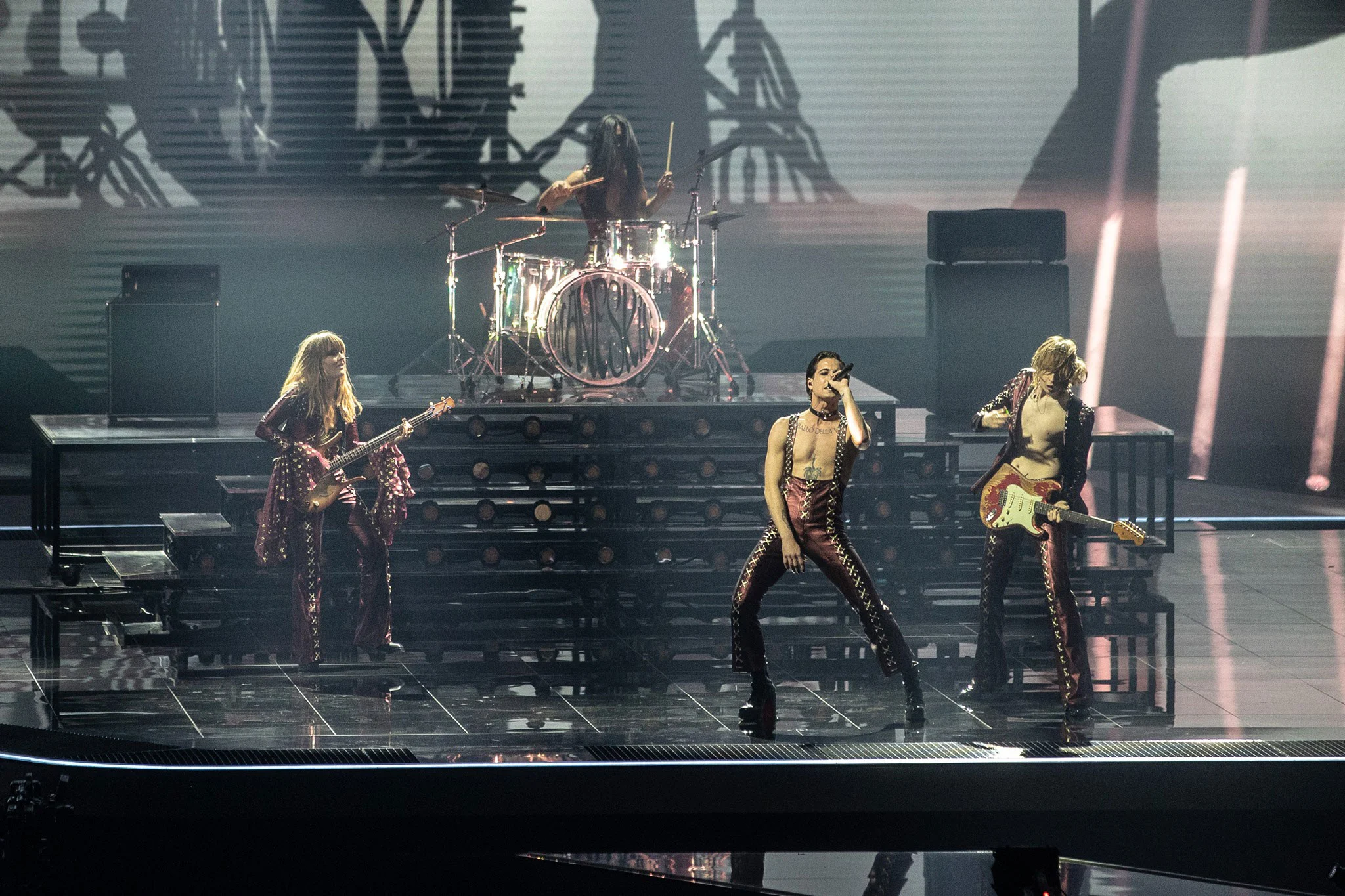 Måneskin performing on stage, drum kit raised on illuminated steps behind them – Måneskin at Eurovision 2021, Rotterdam, Netherlands – concert stage design