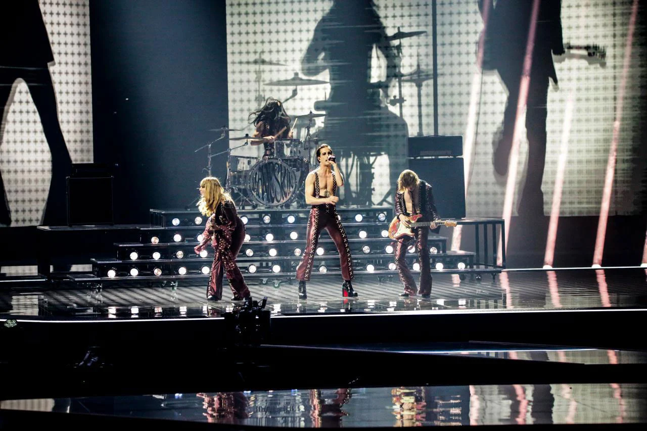 The band on stage in front of a backdrop showing an oversized drummer silhouette – Måneskin at Eurovision 2021, Rotterdam, Netherlands – concert stage design