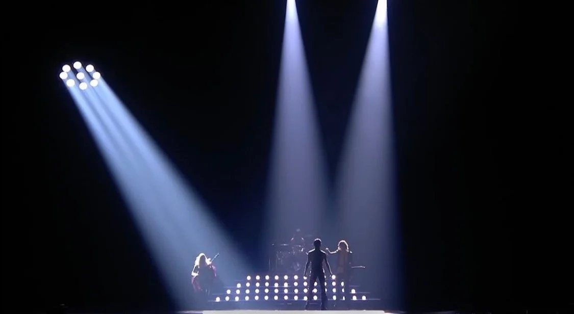 Darkened stage lit only by three white spotlights on the band – Måneskin at Eurovision 2021, Rotterdam, Netherlands – concert stage design