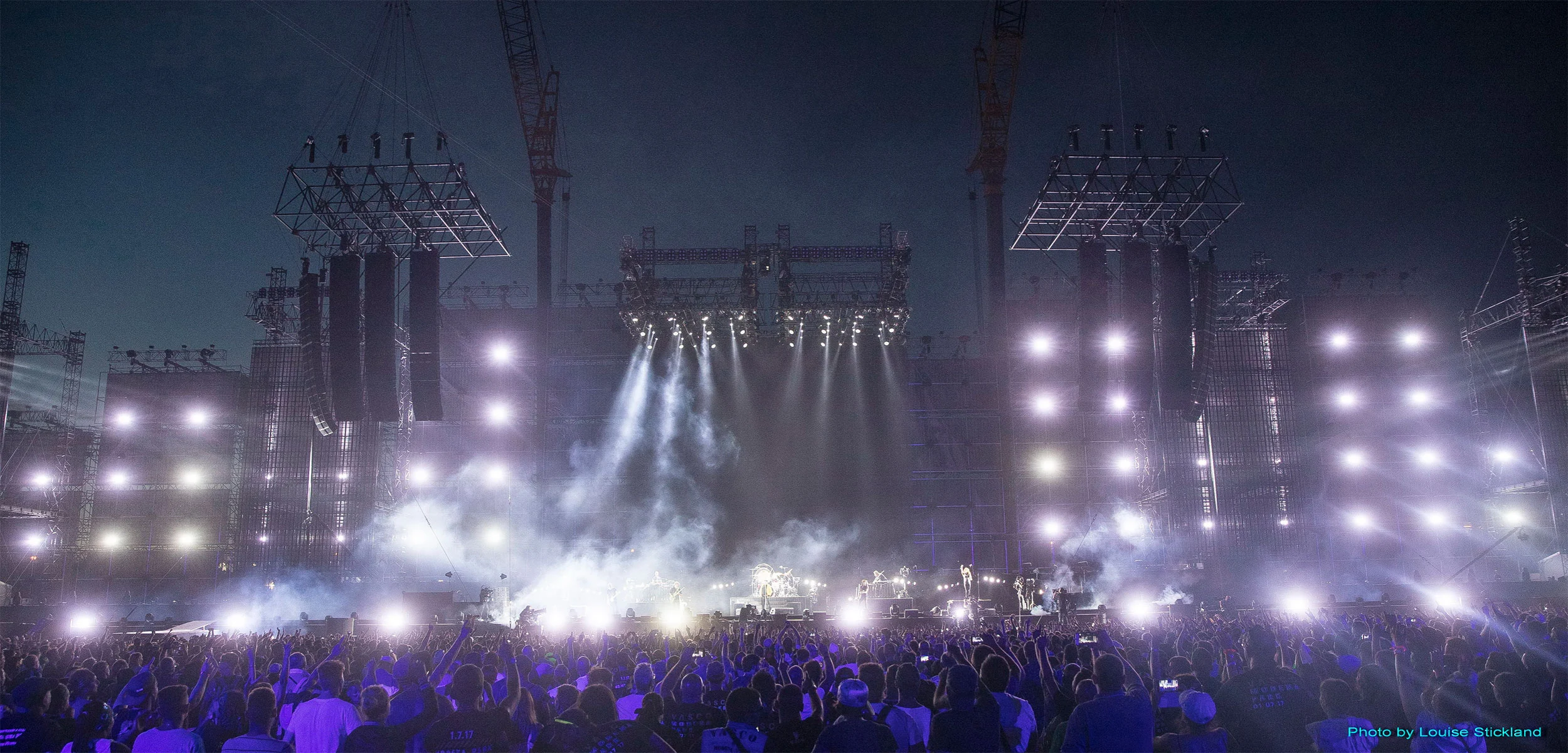 Wide night view of the stage with rows of white lights on the towers and haze rising over the crowd – Vasco Rossi Modena Park, Italy, 2017 – concert stage design
