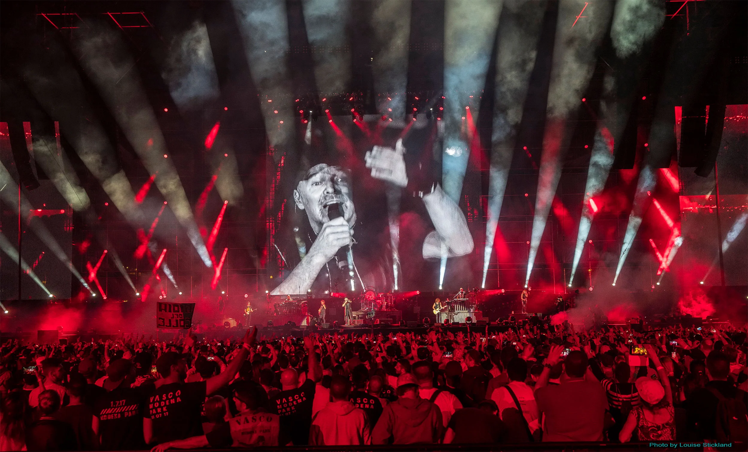 Vasco Rossi on a giant screen above the band, stage bathed in red light and smoke during the concert – Vasco Rossi Modena Park, Italy, 2017 – concert stage design