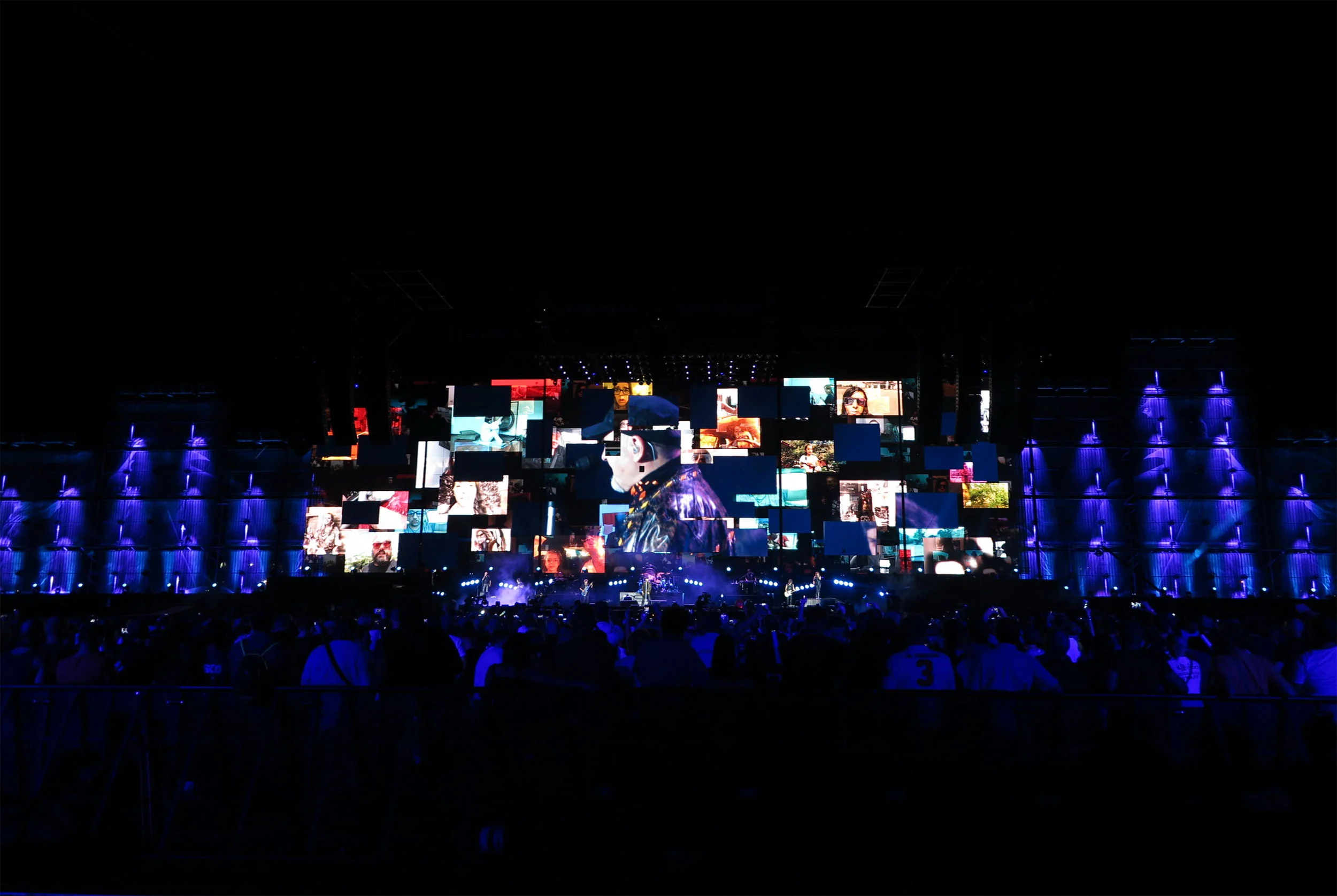 Night view of the Modena Park stage: a mosaic of video screens framed by towers lit in violet before the crowd – Vasco Rossi Modena Park, Italy, 2017 – concert stage design