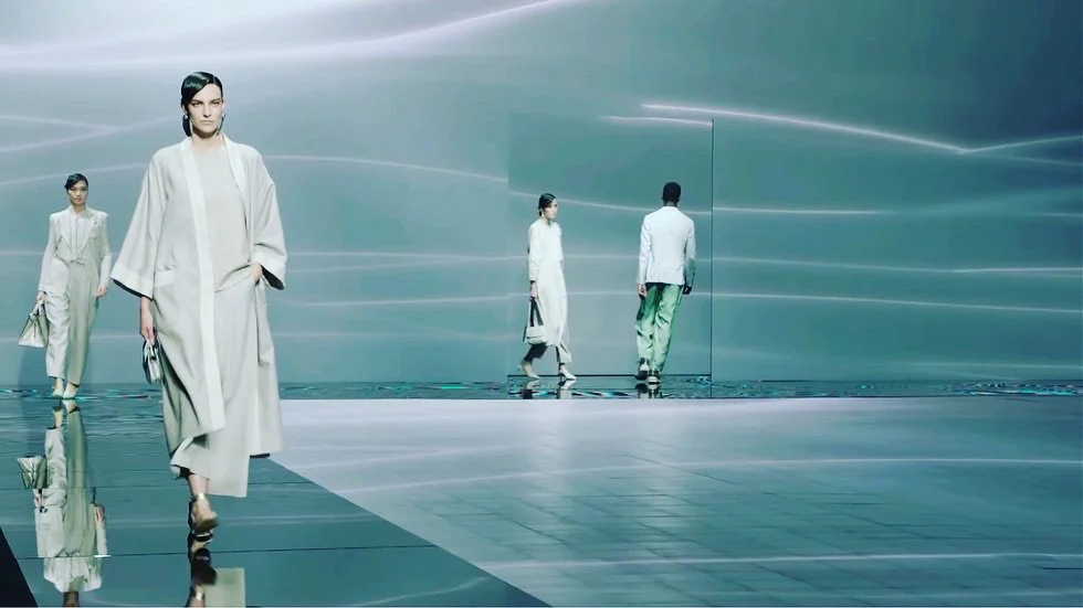 Models walking on a mirrored floor against pale grey-green walls with soft streaks of light – Giorgio Armani SS21 Womenswear, Milan, Italy, 2021 – fashion show set design