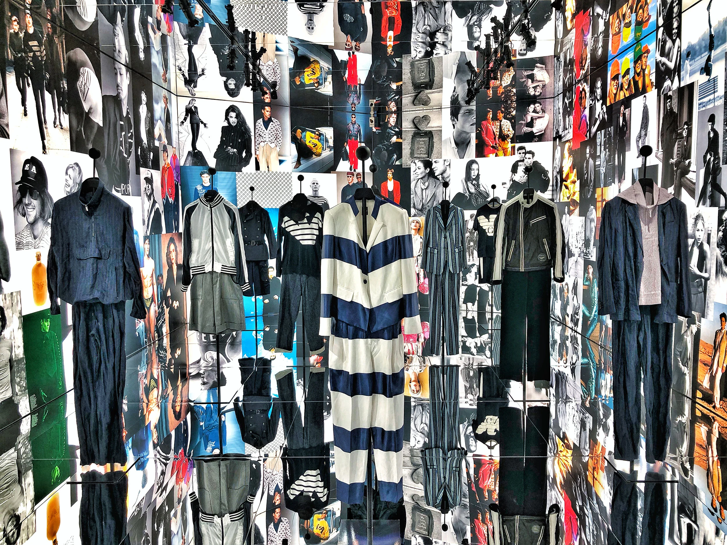 Garments on stands in a mirrored room lined floor to ceiling with fashion photographs – Emporio Armani The Way We Are, Milan, Italy, 2020 – exhibition design