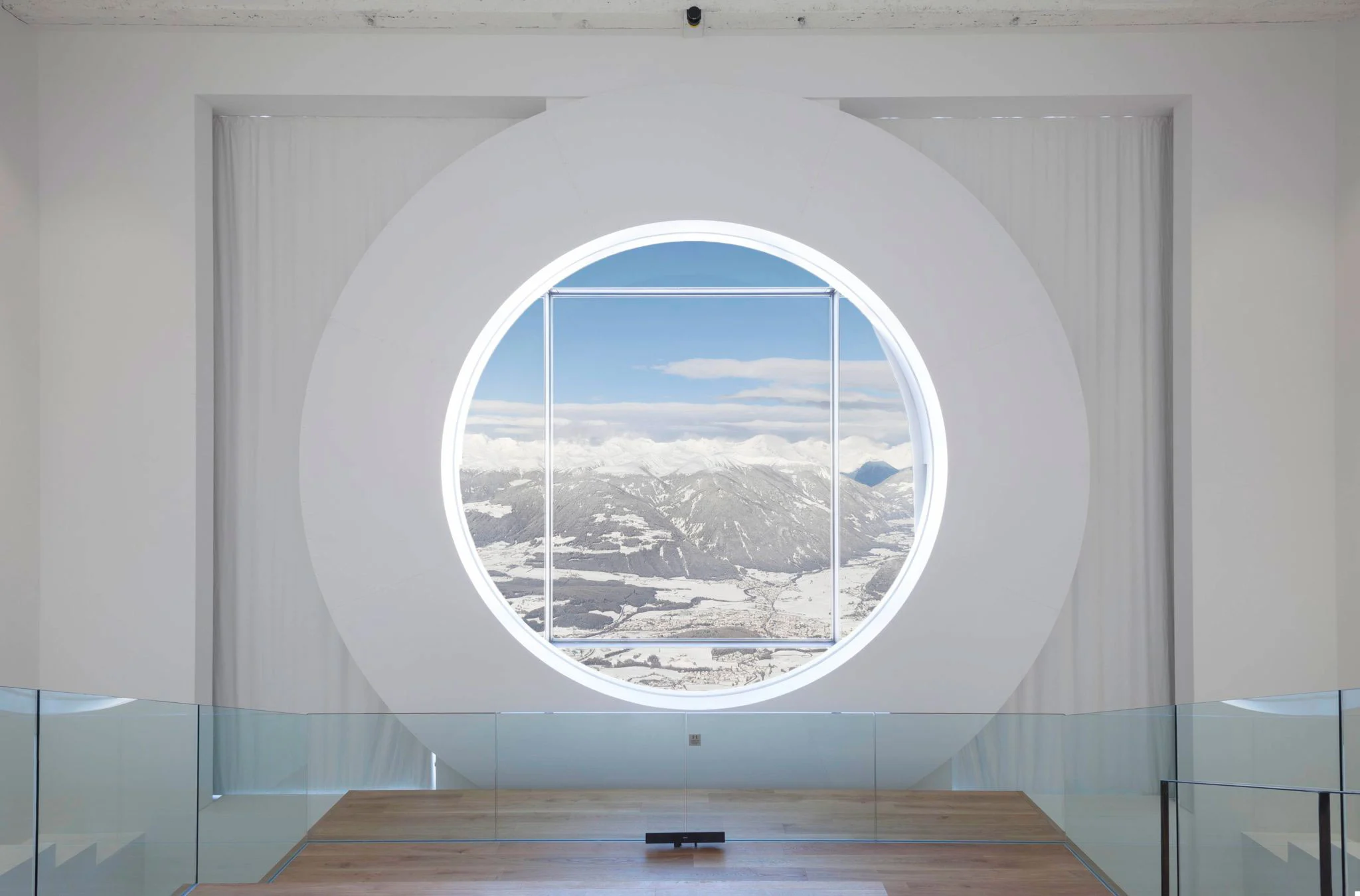 Large circular window set in a white wall, framing a wide view of the snowy valley below – Lumen Museum of Mountain Photography, Kronplatz, Italy, 2018 – architecture