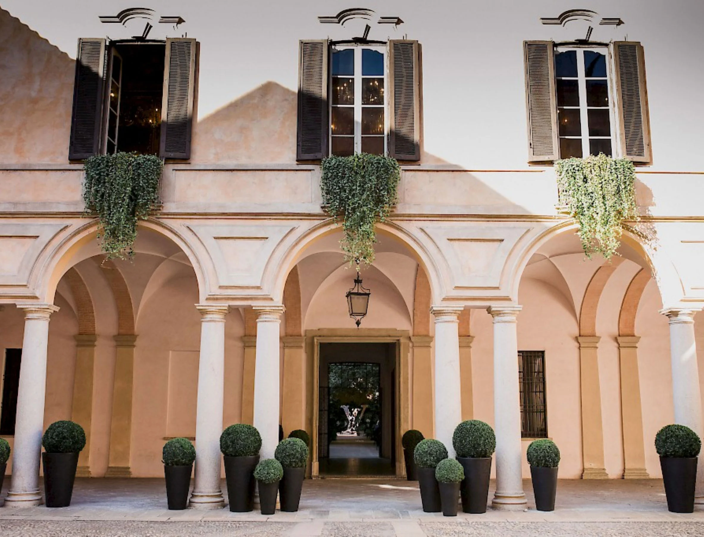 Palazzo Clerici courtyard facade with hanging greenery under the windows and potted topiary balls – Louis Vuitton at Palazzo Clerici, Milan, Italy, 2019 – exhibition design