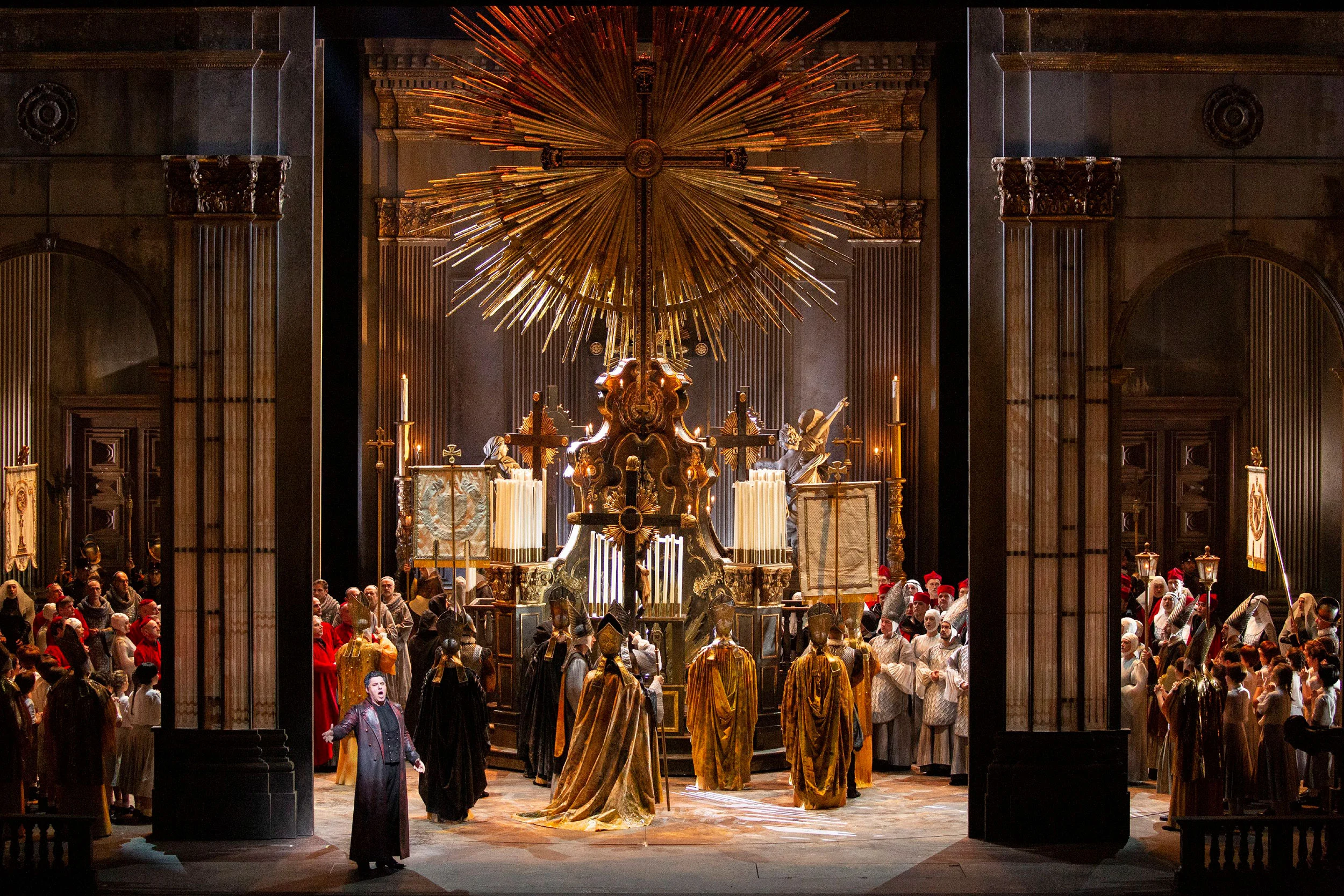 Church set with a towering gilded sunburst cross above an altar, crowds of clergy on both sides – Tosca at La Scala, Milan, Italy, 2019 – opera set design