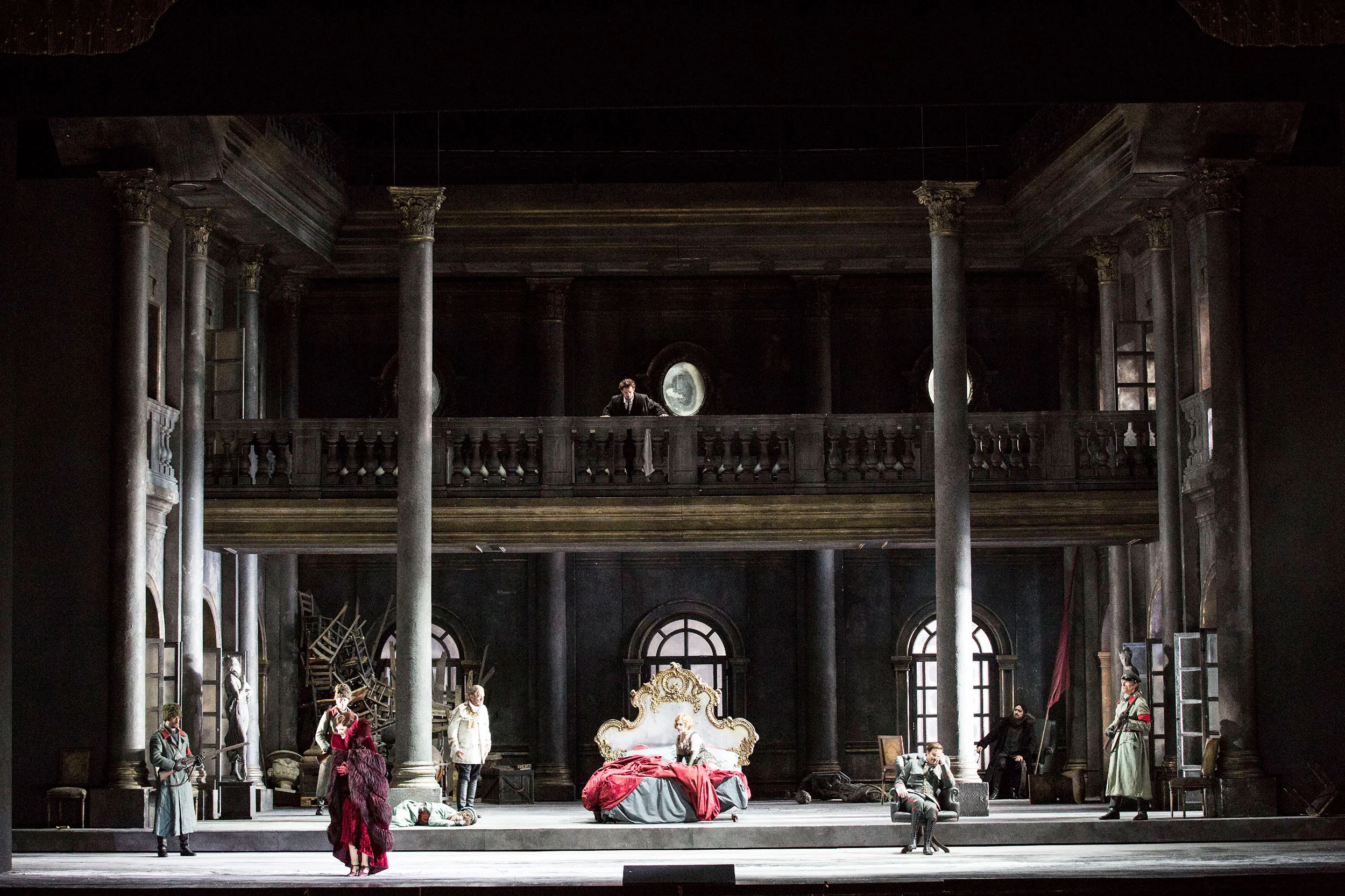 Palace interior set with columns, an upper gallery and a gilded bed at centre, performers around it – Tamerlano at La Scala, Milan, Italy, 2017 – opera set design