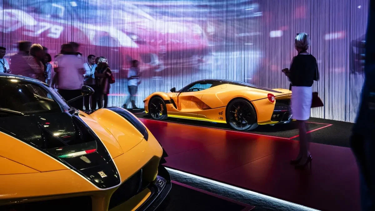 Yellow Ferrari supercars on a red-lit platform before a wall of string curtains with projected video – Universo Ferrari at Fabbrica del Vapore, Milan, Italy, 2019 – exhibition design