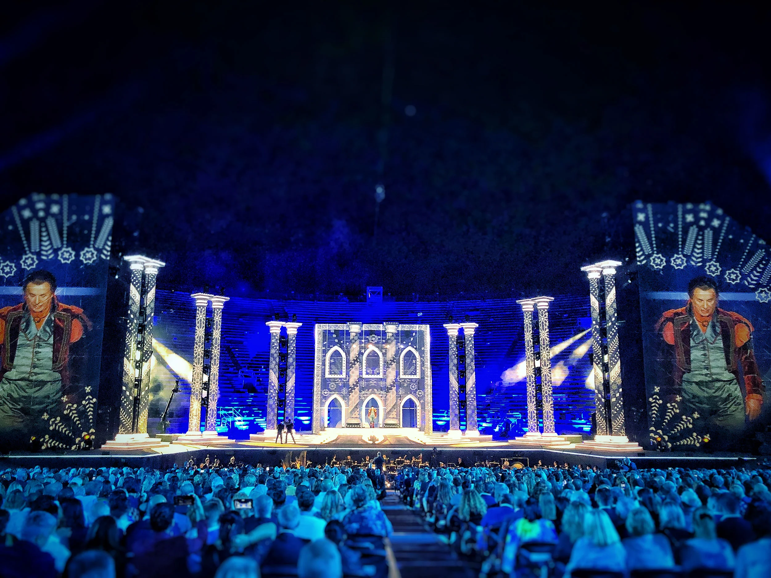 Stage bathed in blue light, with patterned columns, a lit Gothic-style facade and close-ups of a performer on side screens – La Notte di Andrea Bocelli at the Arena di Verona, Italy, 2018 – concert stage design