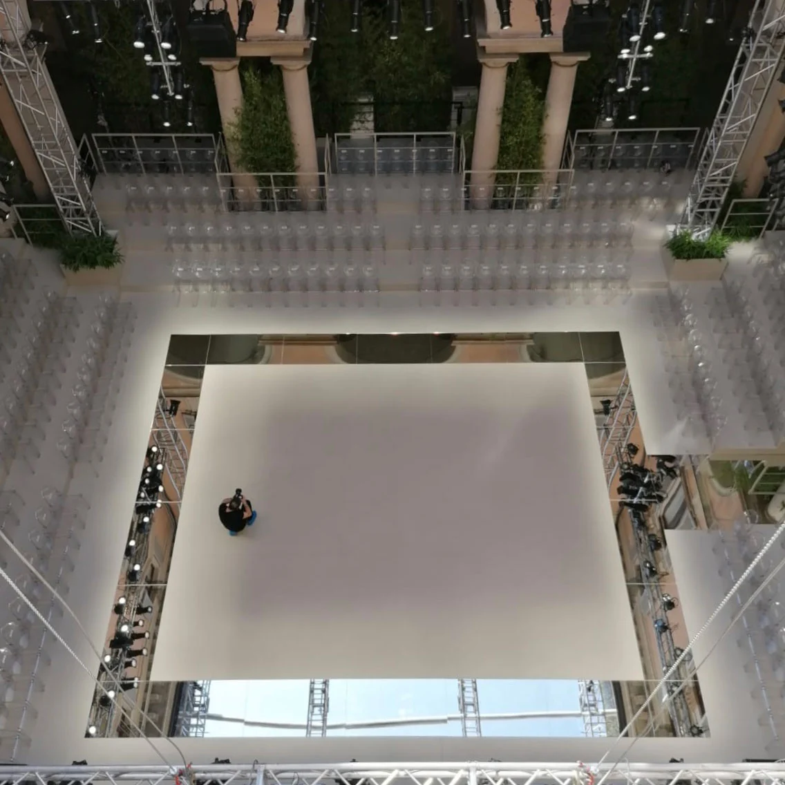 Overhead view of the white catwalk framed by mirrors, clear chairs and lighting trusses – Giorgio Armani SS20 Men and Women, Milan, Italy, 2019 – fashion show set design