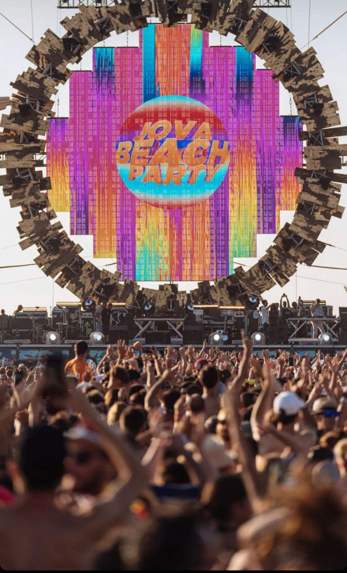 Crowd with raised arms before the ring-framed screen showing the Jova Beach Party logo – Jova Beach Party 2019, Italy – concert stage design