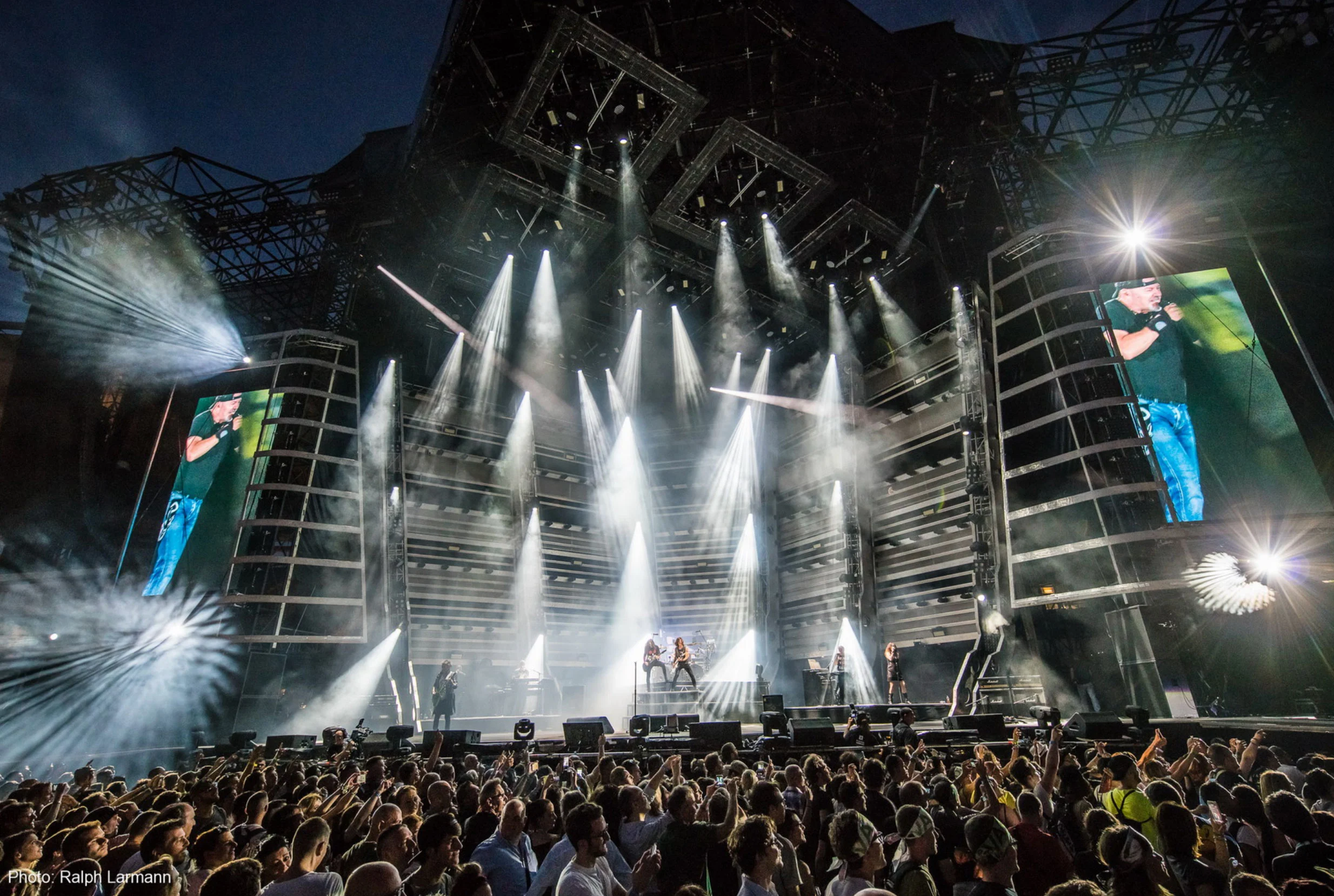 Vasco Live Kom stadium stage with white light beams, angular truss framework and side video screens – Vasco Rossi Live Kom 2016, Italy – concert stage design