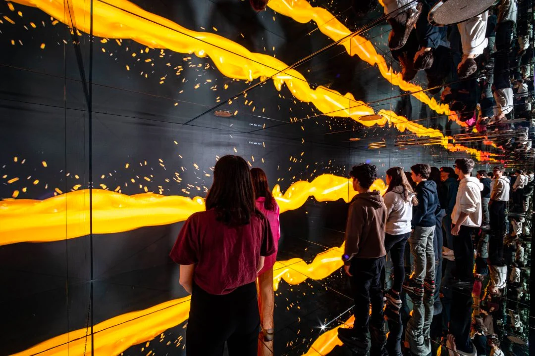 Visitors in a mirrored room surrounded by screens with flowing streams of yellow light – STEP FuturAbility District by Fastweb, Milan, Italy, 2022 – exhibition design