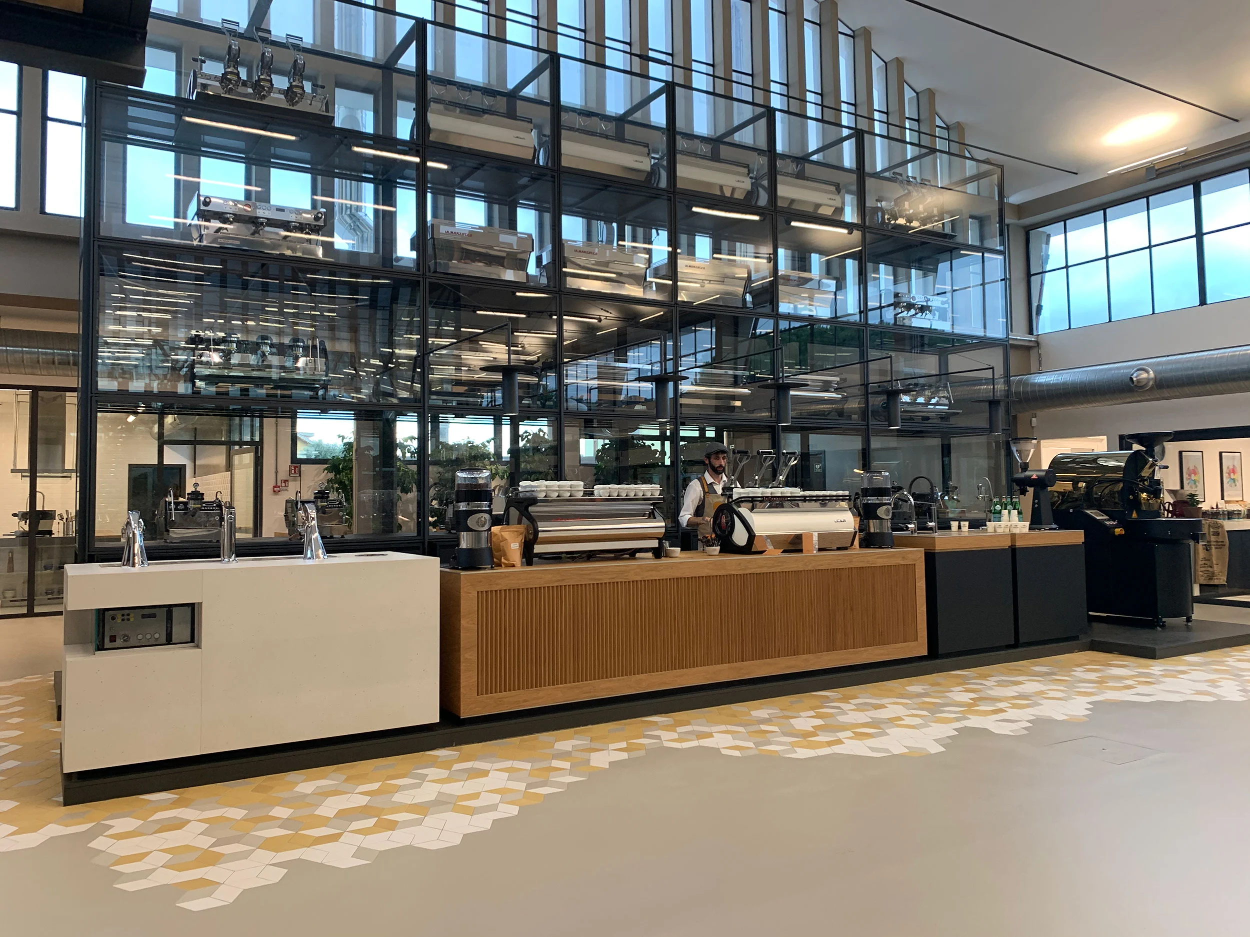 Wide view of the coffee bar and multi-level glass display case in the converted factory hall – La Marzocco Accademia del Caffè Espresso, Florence, Italy, 2018 – interior design