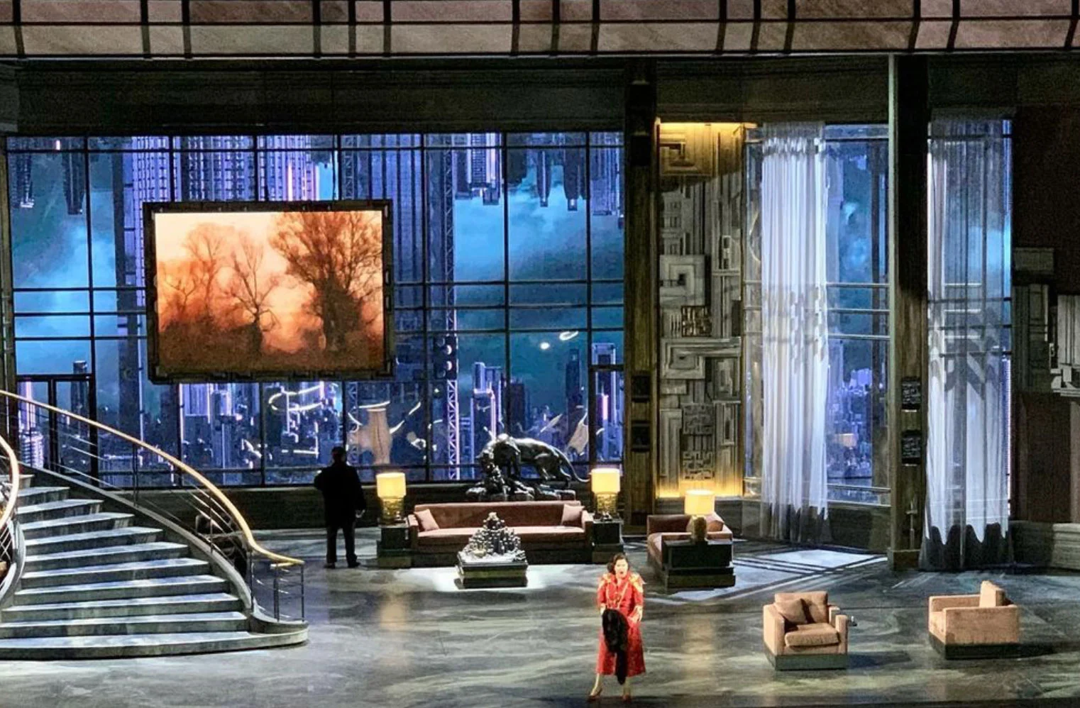 Luxury penthouse set with sofas, a sweeping staircase and a glass wall onto a night skyline – Macbeth at La Scala, Milan, Italy, 2021 – opera set design