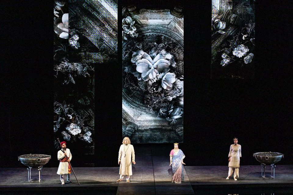 Four singers on a dark stage between two stone basins, with black and white floral projections above – Lakmé at the Royal Opera House Muscat, Oman, 2019 – set design