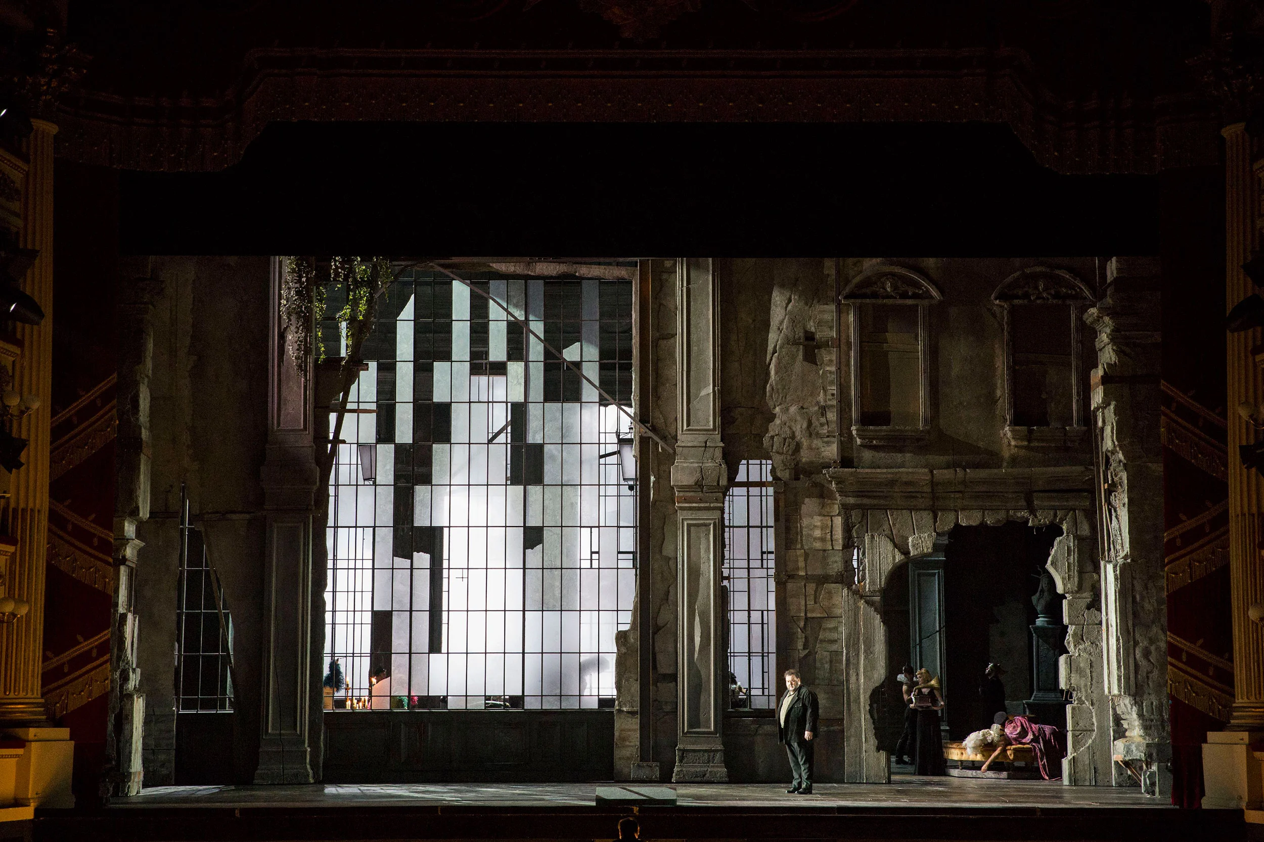 Singer alone in a ruined stone palace, a tall broken glass window lit white behind him – Attila at La Scala, Milan, Italy, 2018 – opera set design