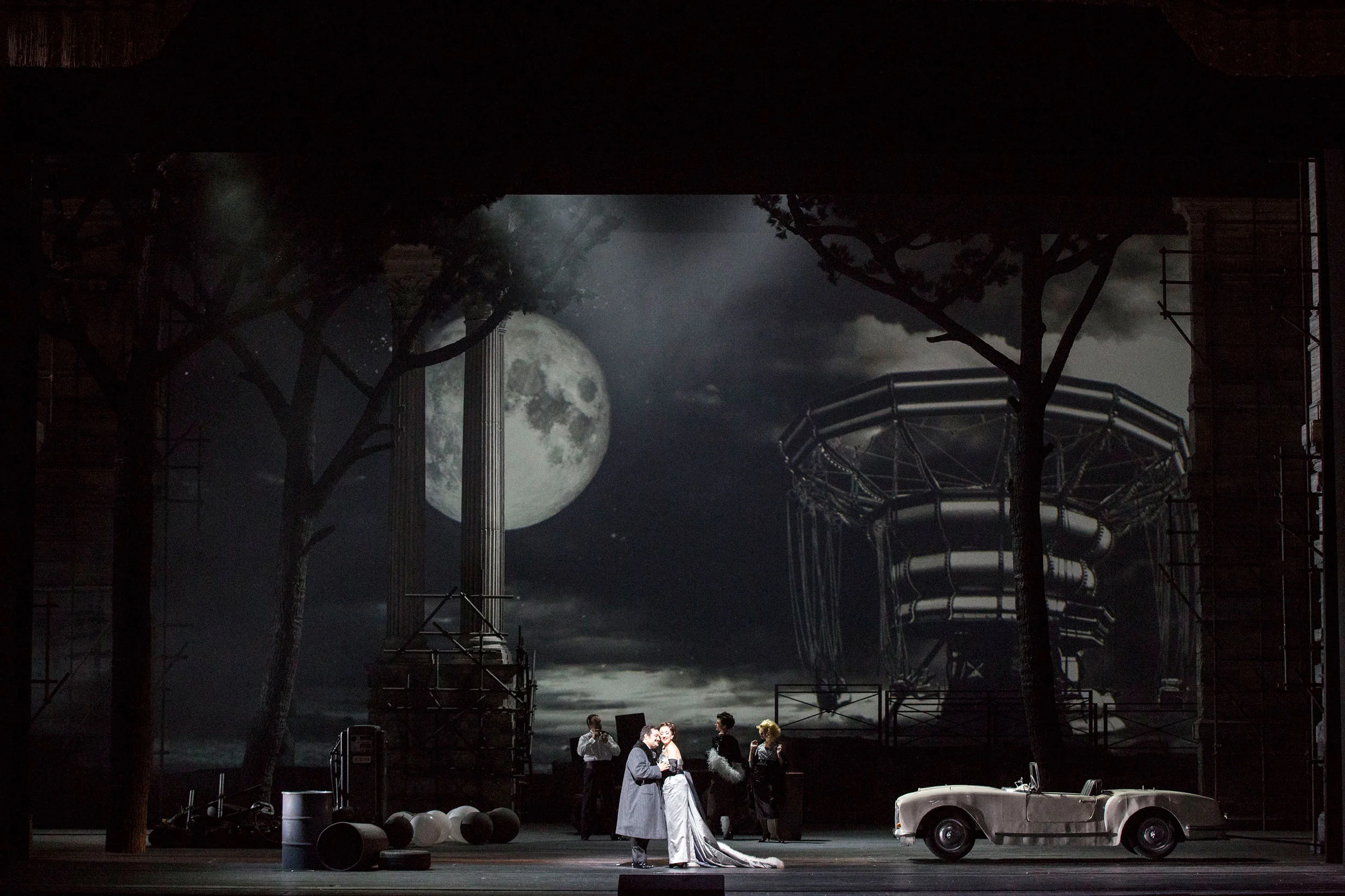 Night scene with a full moon, bare trees, a carousel frame and a white vintage convertible – Don Pasquale at La Scala, Milan, Italy, 2018 – opera set design
