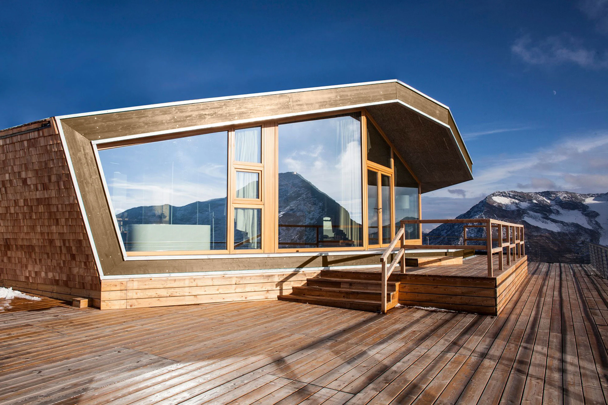 Levissima 3000 Chalet exterior: wood-shingled volume with a large glazed front and a wooden deck facing snowy peaks – Levissima 3000 Chalet, Valdisotto, Italy, 2018 – architecture