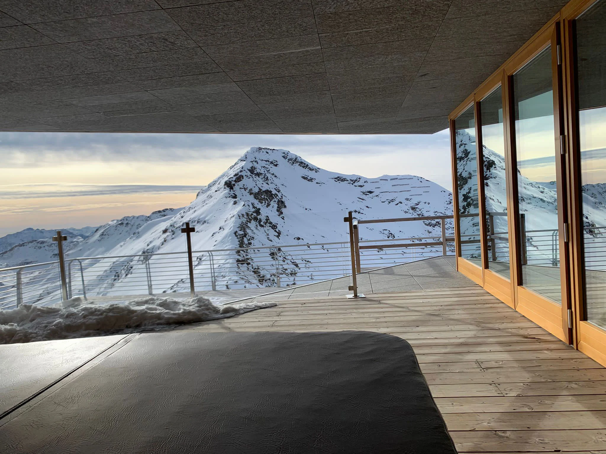 Covered wooden terrace of the chalet looking out at a snow-covered summit at dawn – Levissima 3000 Chalet, Valdisotto, Italy, 2018 – architecture