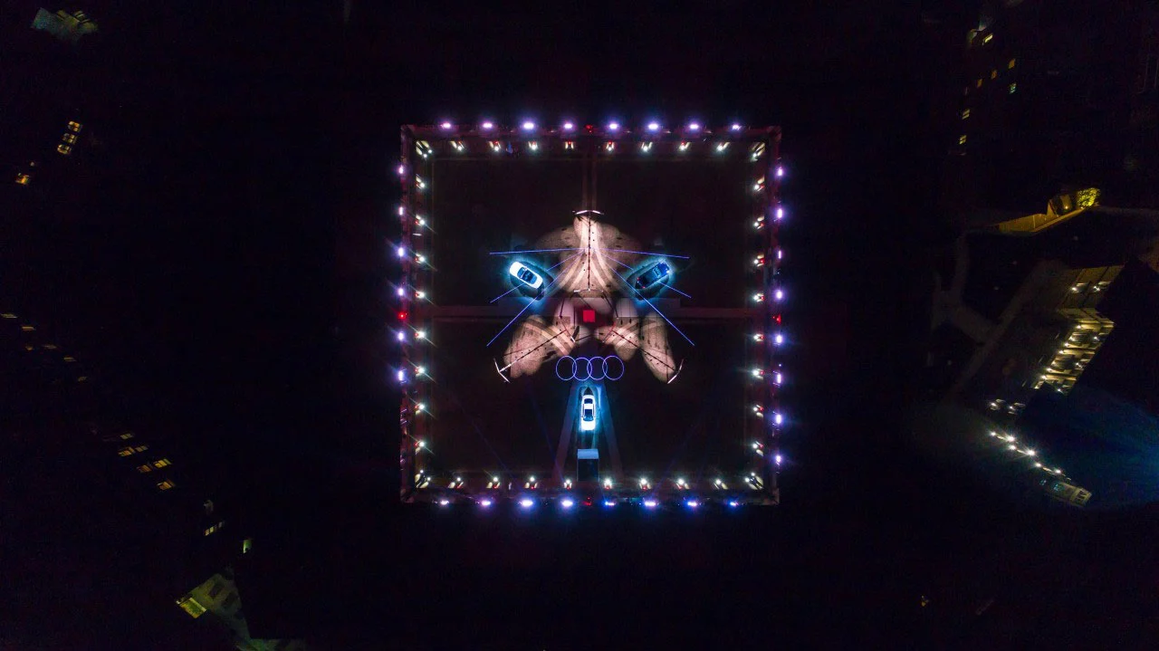 Aerial night view of the Audi City Lab courtyard: square lit outline, light graphics on the ground and cars – Audi City Lab at Fuorisalone, Milan, Italy, 2017 – event design