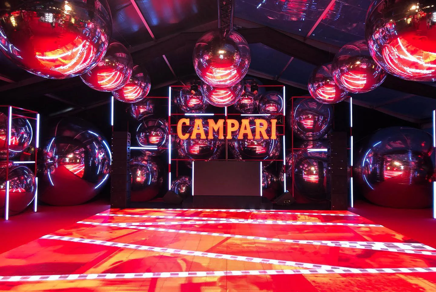 Campari party dance floor of red LED panels under giant mirrored spheres, the Campari sign behind the DJ booth – Campari at the 75th Cannes Film Festival, France, 2022 – event design