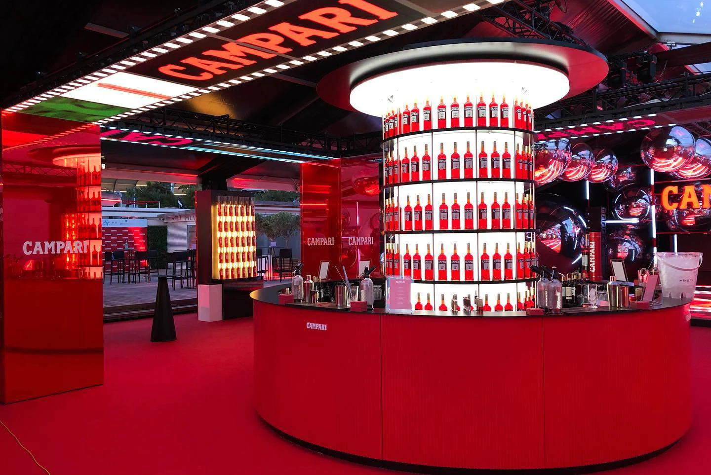 Circular red Campari bar with a backlit bottle tower, surrounded by mirrored spheres and red columns – Campari at the 75th Cannes Film Festival, France, 2022 – event design