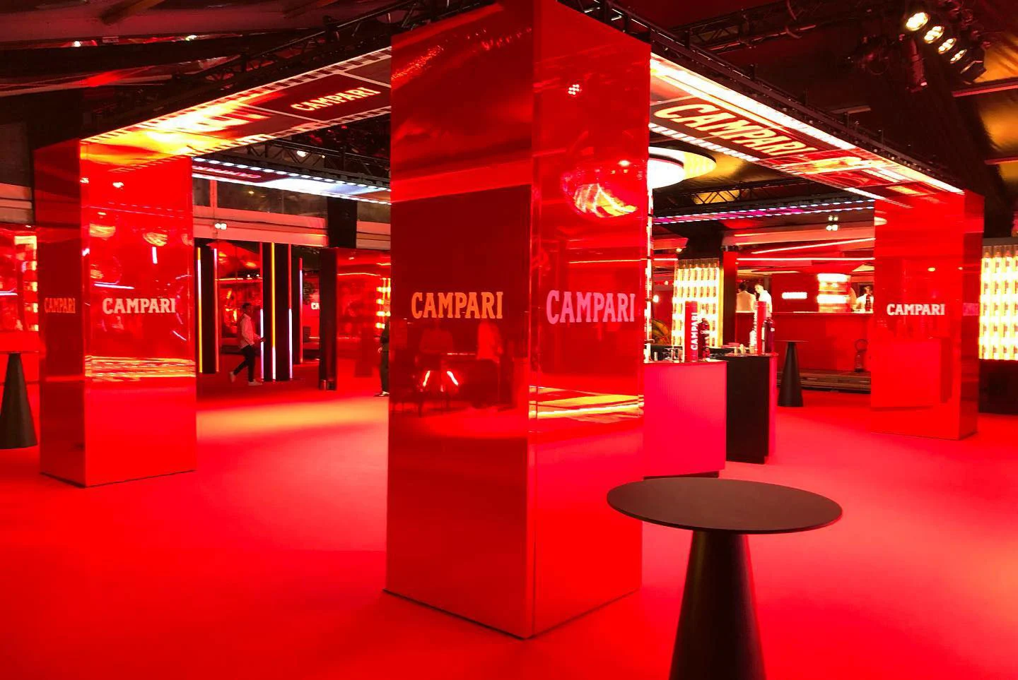 Red-carpeted lounge with mirrored red columns bearing the Campari logo and high cocktail tables – Campari at the 75th Cannes Film Festival, France, 2022 – event design