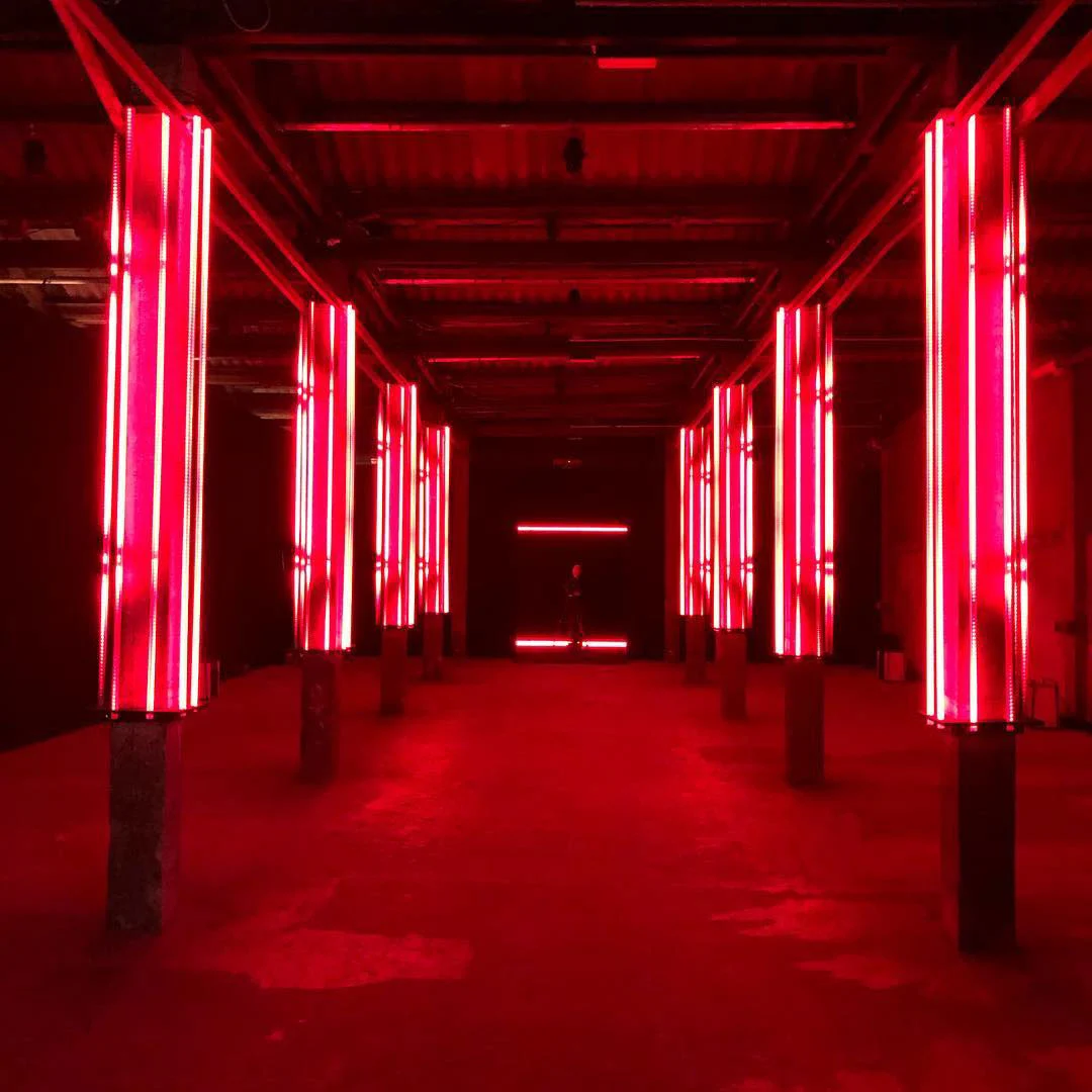 Long industrial hall in red light, lined with pillars wrapped in vertical neon tubes – Campari Red Diaries, Milan, Italy, 2017 – event design