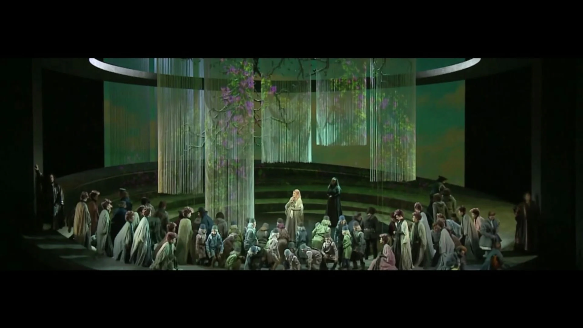 Chorus gathered on the round stage among string curtains projected with a blossoming tree – Otello at Teatro Carlo Felice, Genoa, Italy, 2014 – opera set design