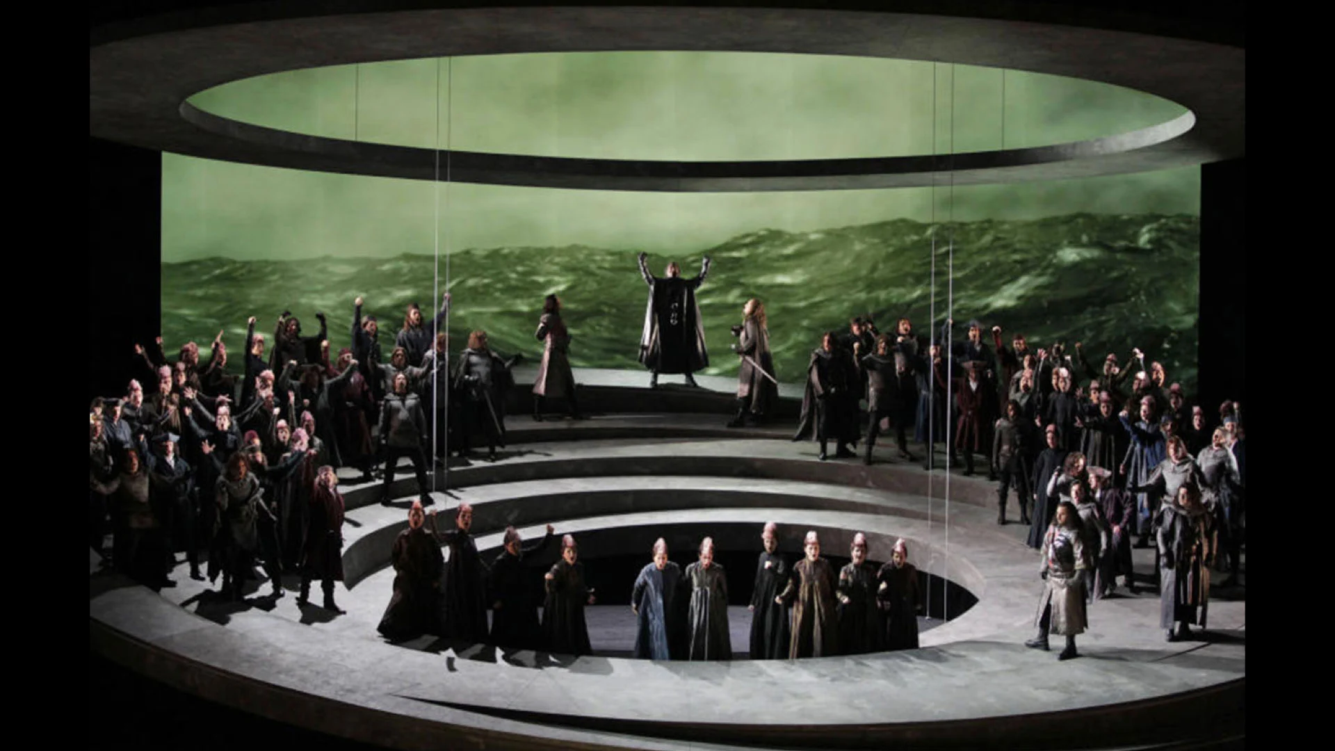 Otello staged at Teatro Carlo Felice: chorus on circular tiers before a projection of a stormy sea – Otello at Teatro Carlo Felice, Genoa, Italy, 2014 – opera set design