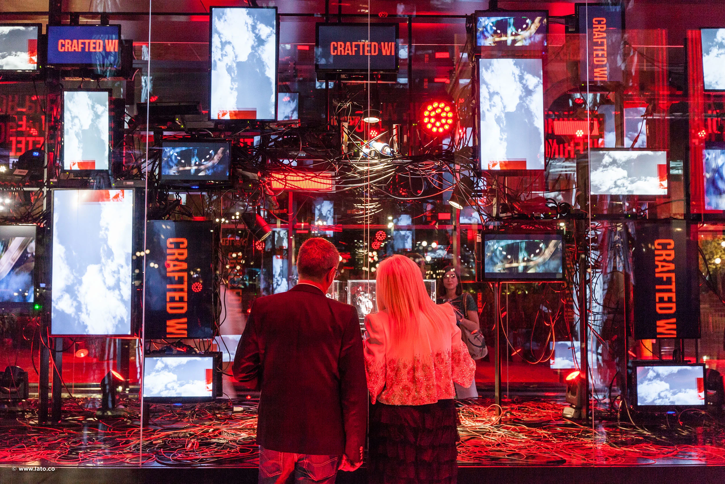 Visitors facing a red-lit wall of screens showing clouds, with Crafted Wi... banners and cables – Cartier The Legendary Thrill, Milan, Italy, 2018 – event design