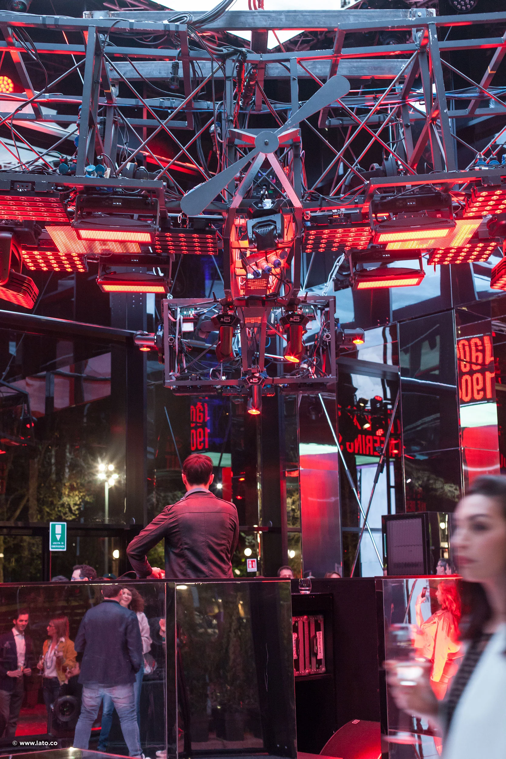Inside the pavilion: a suspended propeller and red lights hang from a steel truss above visitors – Cartier The Legendary Thrill, Milan, Italy, 2018 – event design