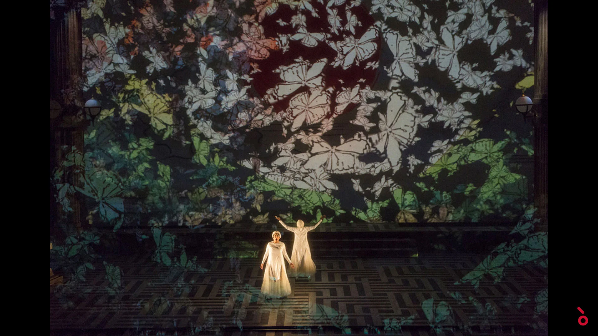 Two women in white on a dark stage covered by a projected pattern of butterflies and leaves – The Opera! at the Royal Opera House Muscat, Oman, 2019 – set design