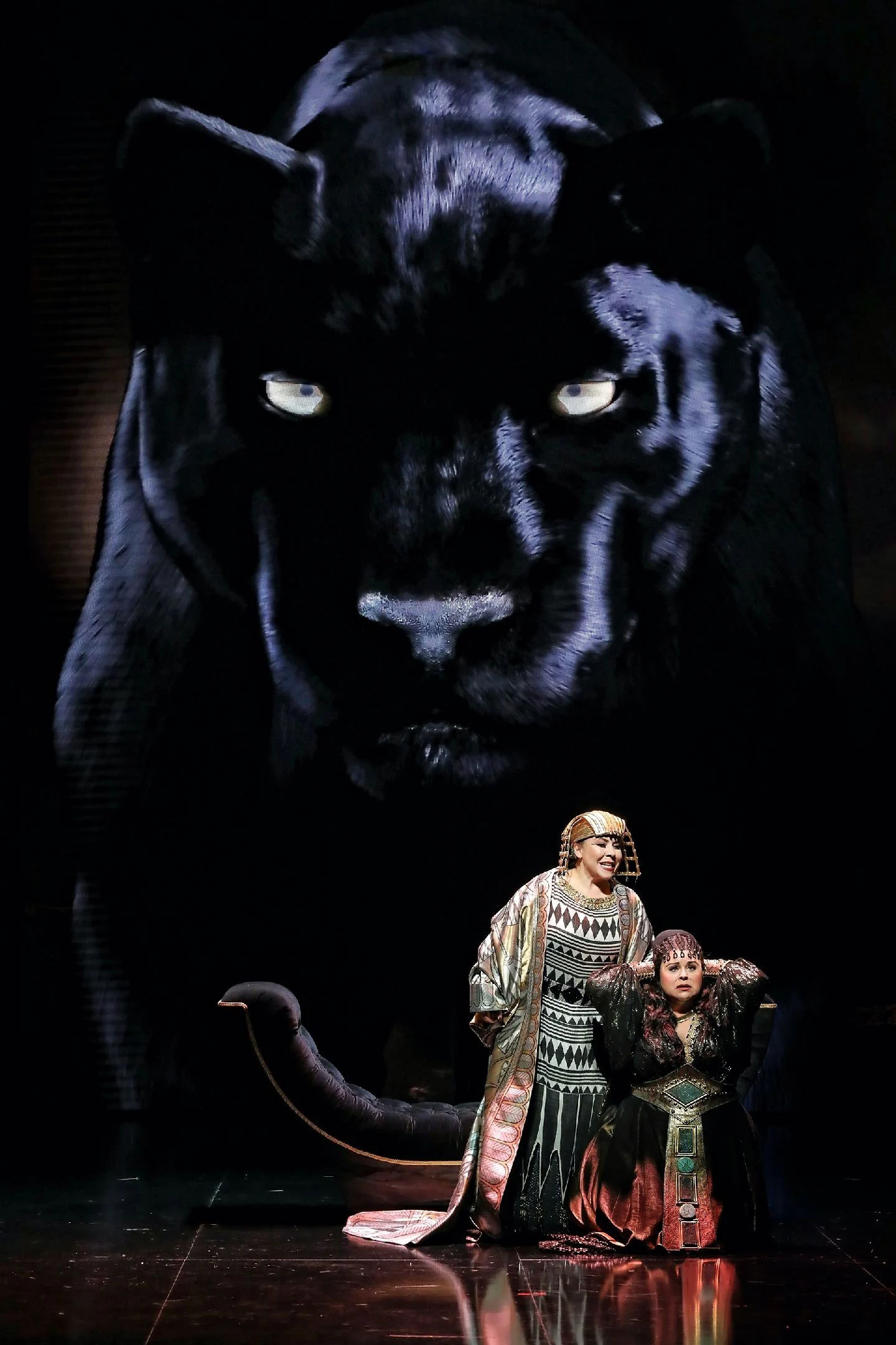Two singers in Egyptian costumes kneeling beneath a giant video image of a black panther – Aida at Sydney Opera House, Australia, 2018 – set design