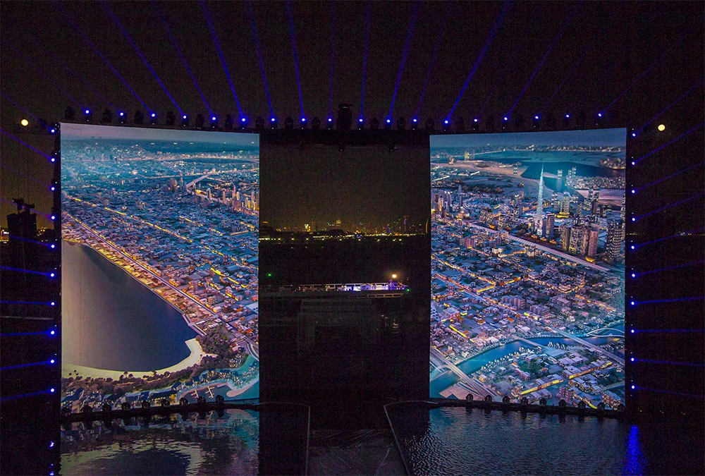 Two side screens showing aerial night views of the Dubai coastline, with the city lights between them – Dubai Water Canal Opening Ceremony, United Arab Emirates, 2016 – event design