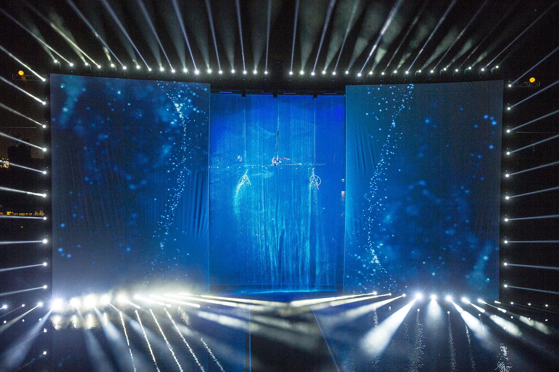 Opening ceremony stage on the water: three blue-lit screens with aerial performers suspended over a waterfall – Dubai Water Canal Opening Ceremony, United Arab Emirates, 2016 – event design