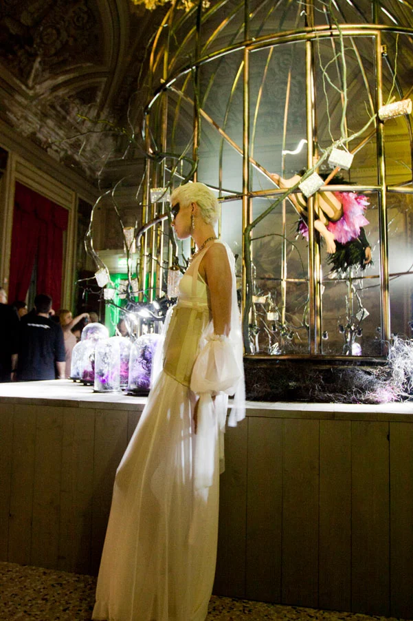 Model in a long white gown posing beside the giant golden birdcage with jewel displays – Swarovski Fashionation Party at Palazzo Reale, Milan, Italy, 2011 – event design