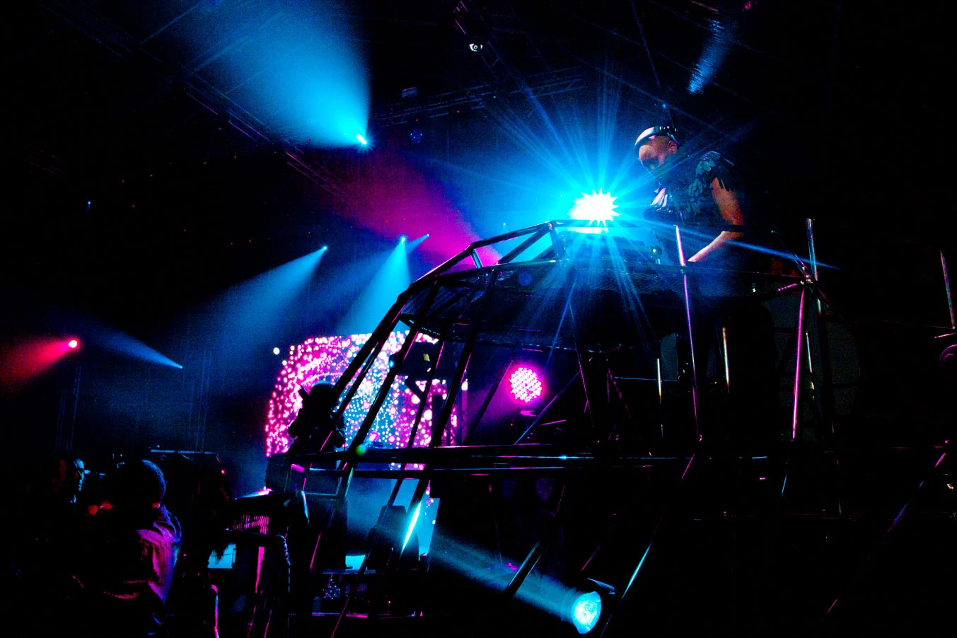 DJ booth on a metal-frame structure lit by blue and pink beams, with an LED screen in the background – Swarovski Fashionation Party at Palazzo Reale, Milan, Italy, 2011 – event design