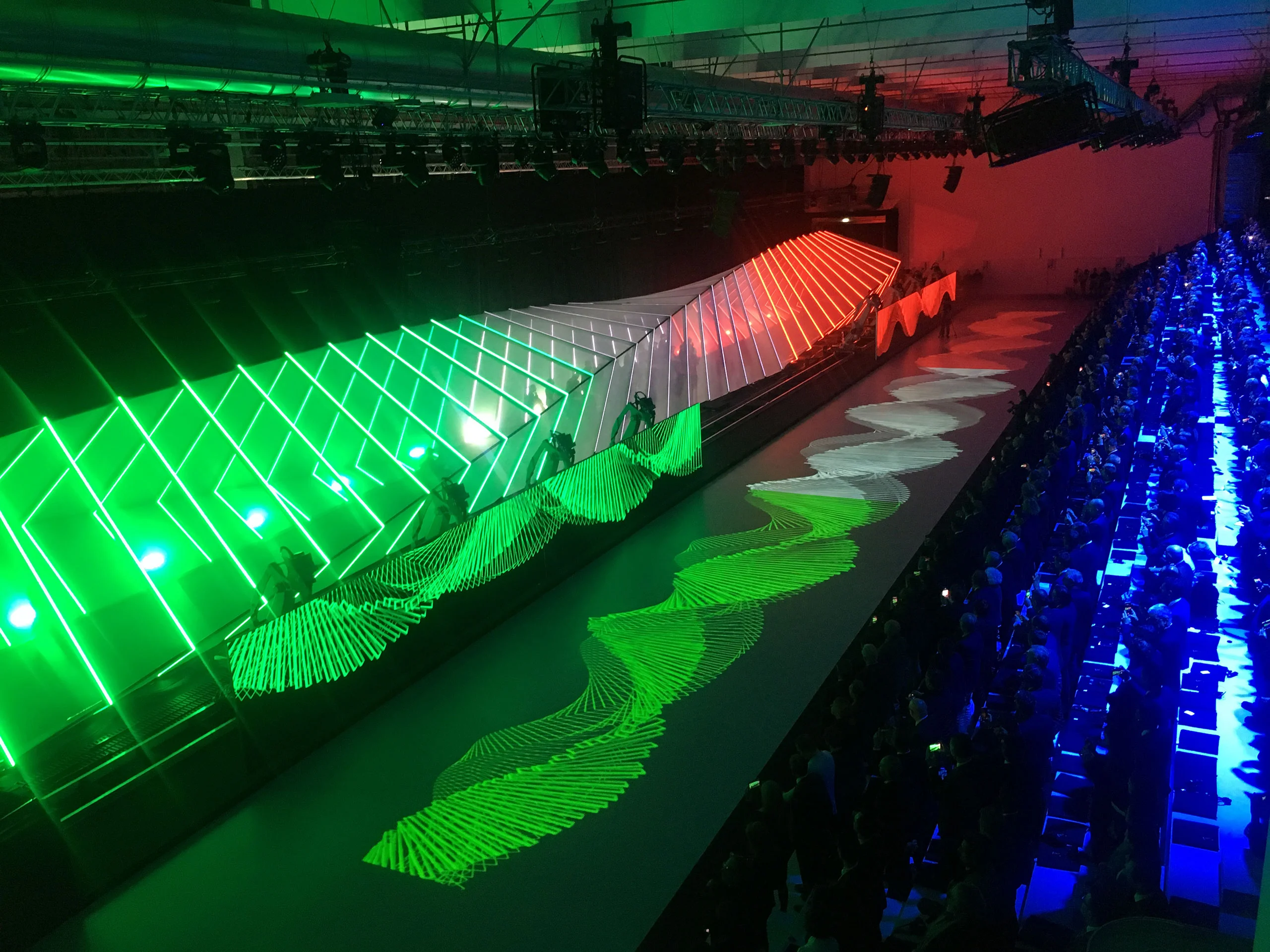 Undulating green, white and red light structure with a wave projected on the floor beside the audience – Lamborghini Urus World Premiere, Sant'Agata Bolognese, Italy, 2017 – event design