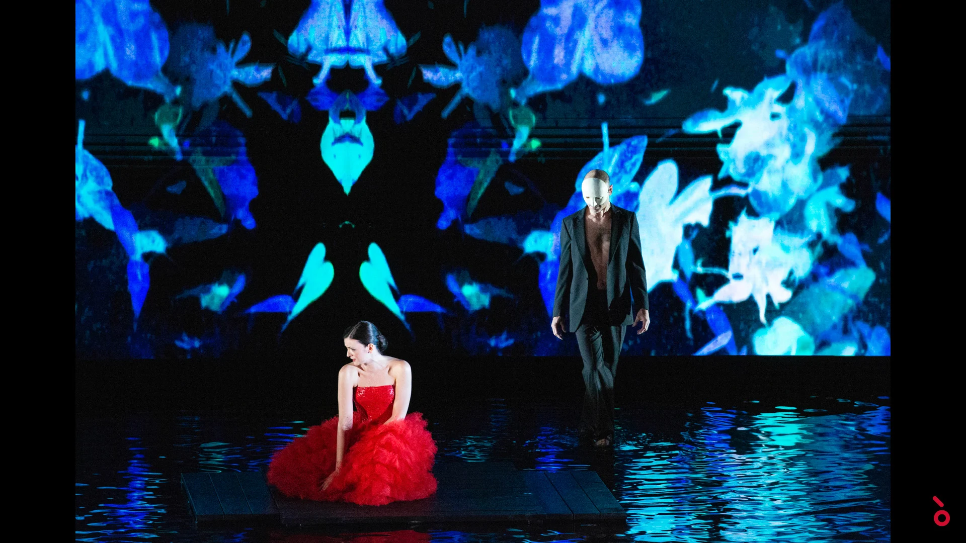 Dancer in a red tulle dress on a platform over a water floor, blue kaleidoscopic projection behind – A Riveder le Stelle at La Scala, Milan, Italy, 2020 – opera set design