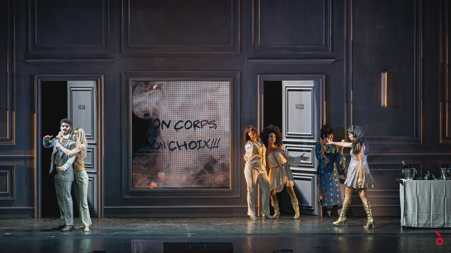 Couples emerging from numbered hotel doors, the slogan "Mon corps, mon choix" projected on a screen – La Traviata at Maggio Musicale Fiorentino, Florence, Italy, 2022 – opera set design
