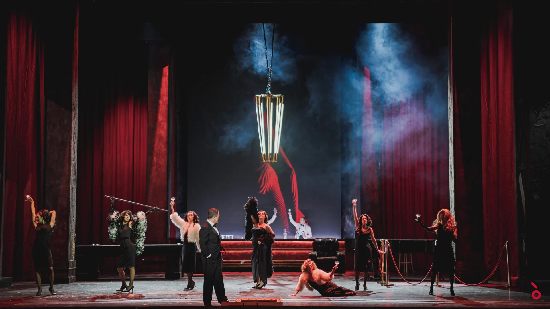 Cabaret scene framed by red velvet curtains, dancers in black around a hanging lantern – Rigoletto at Maggio Musicale Fiorentino, Florence, Italy, 2021 – opera set design