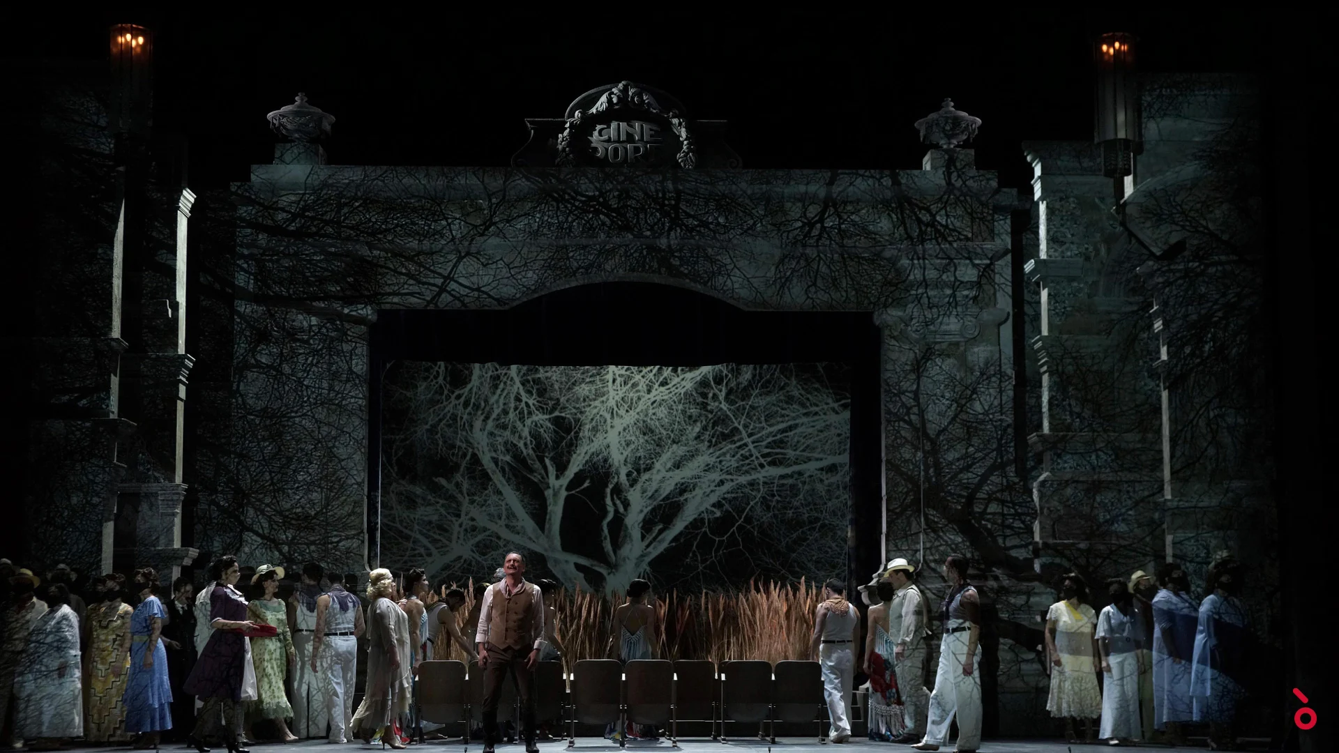 Chorus in front of the ornate cinema facade, a bare tree projected in the arch above rows of seats – Luisa Fernanda at Teatro de la Zarzuela, Madrid, Spain, 2021 – opera set design