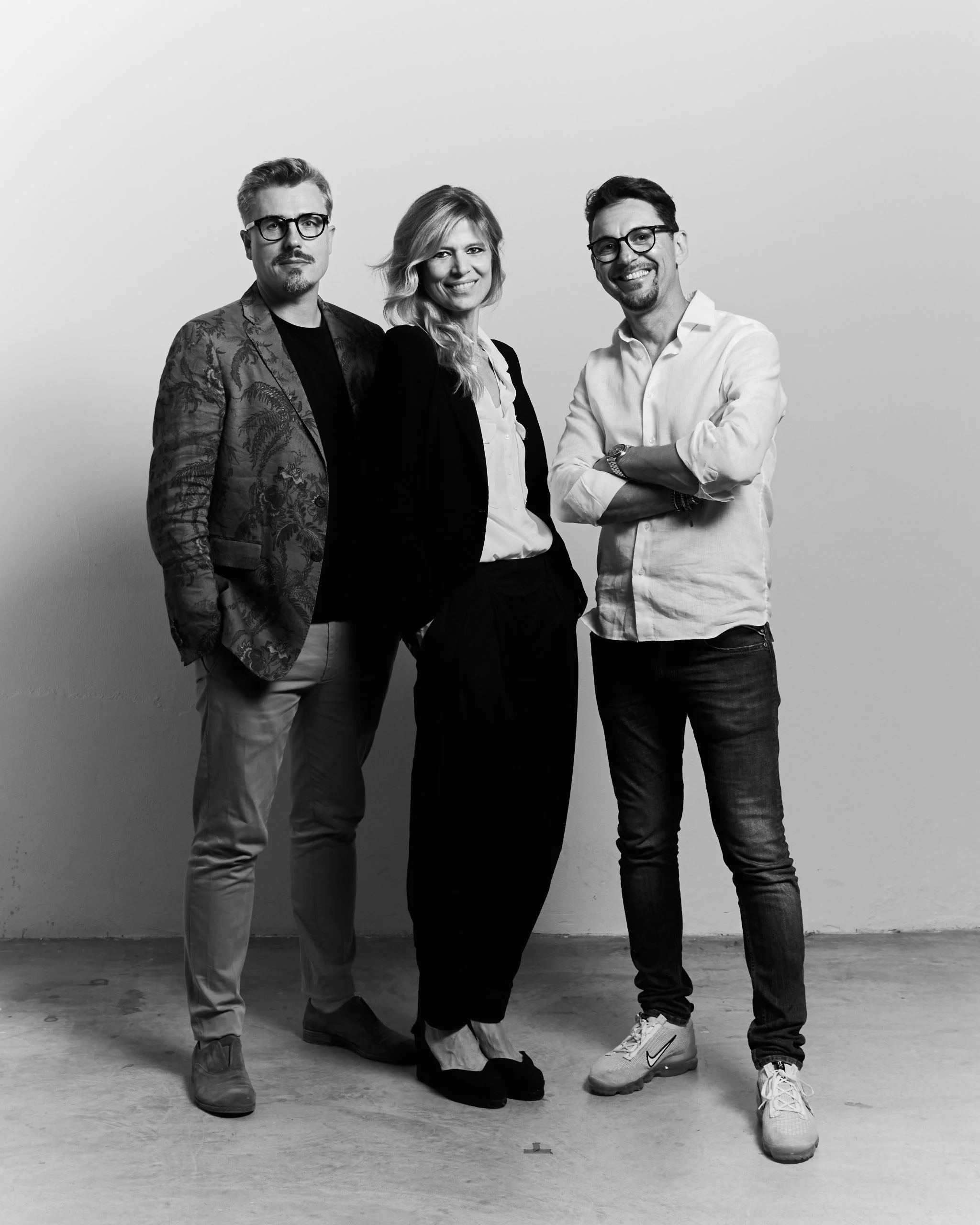 Black-and-white portrait of the three studio founders standing side by side against a plain white wall