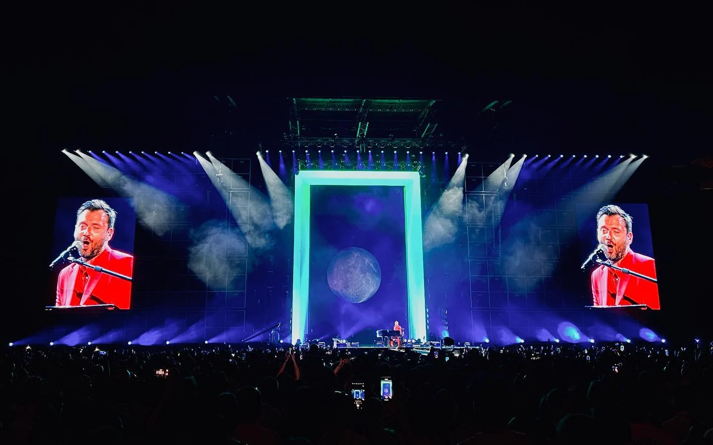 The gate portal glowing green around a moon projection, Cesare Cremonini at the piano on side screens – Cesare Cremonini Stadi 2022, Italy – concert stage design