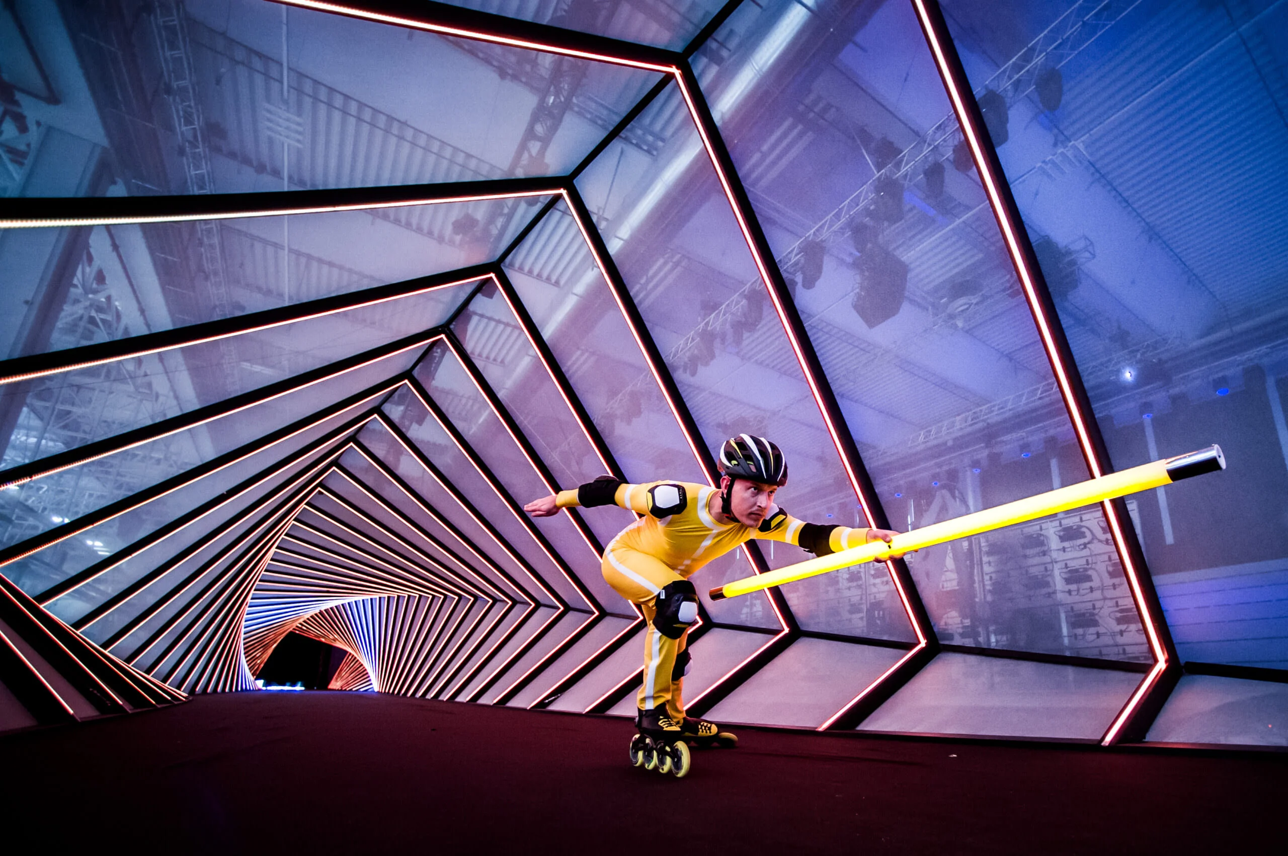Inline skater in a yellow suit carrying a light tube through a tunnel of angled light frames – Lamborghini Urus World Premiere, Sant'Agata Bolognese, Italy, 2017 – event design