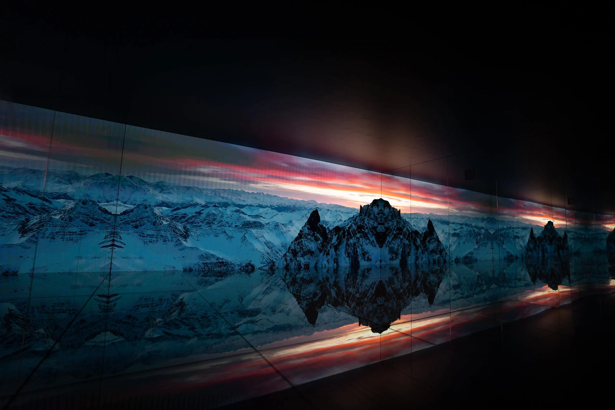 Long LED wall showing mountain peaks under a red sunset sky, reflected in the mirrored floor – Mont Blanc Infinity Room at Skyway, Courmayeur, Italy, 2023 – installation design