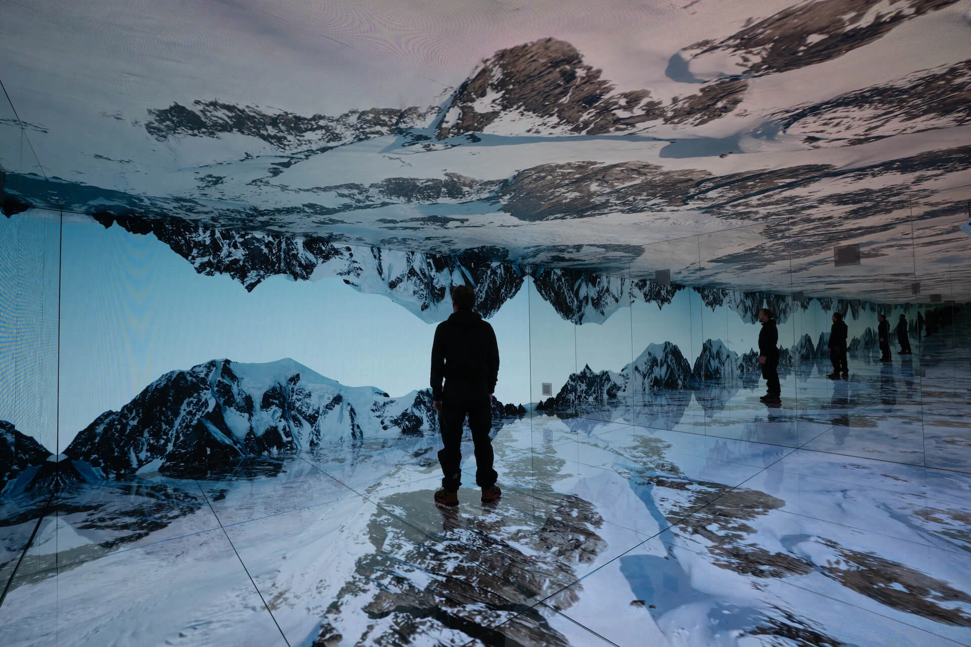 Visitor standing in the Mont Blanc Infinity Room, surrounded by LED walls and mirrors showing snowy peaks – Mont Blanc Infinity Room at Skyway, Courmayeur, Italy, 2023 – installation design